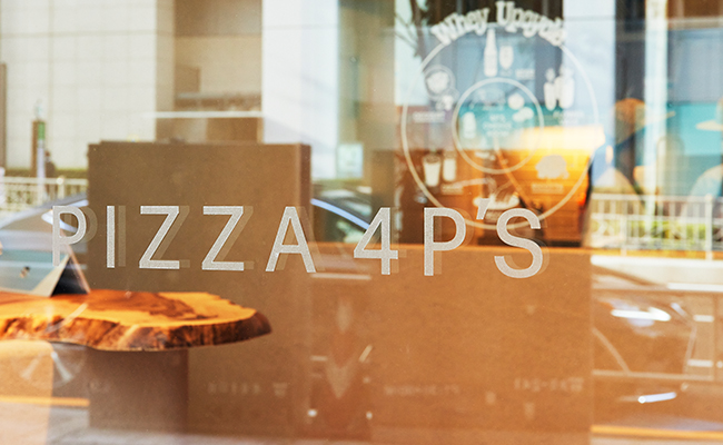 Pizza 4P's Tokyoのドアに映るロゴ
